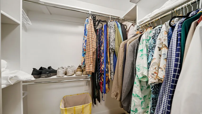 Expansive closet featuring multiple clothing rods, integrated shelving, and white walls