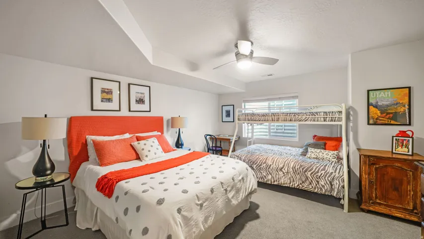 Spacious bedroom featuring carpet flooring, a ceiling fan, and a window with blinds