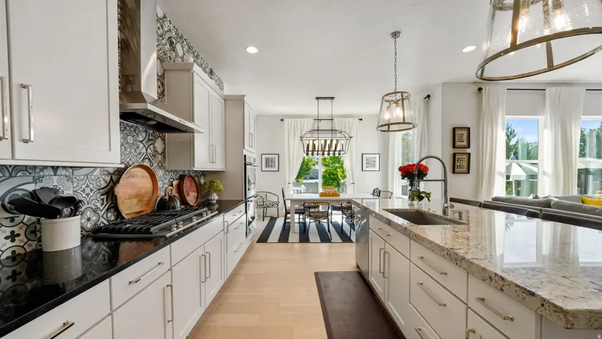 Gourmet kitchen featuring a gas range, stainless steel range hood, white cabinetry, and contrasting black and light-toned countertops