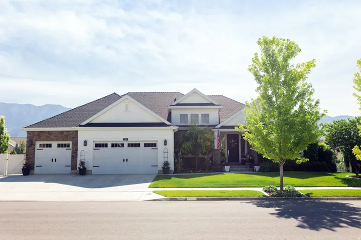 Traditional-style residence featuring a combination of over grouted stone and siding, a three-car garage, and additional concrete parking.