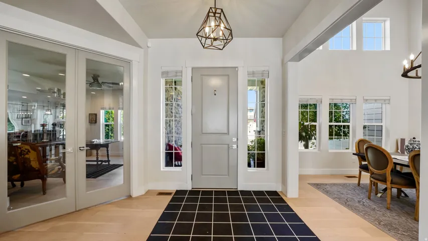 Grand foyer featuring a light gray entry door, side window panels, and an overhead geometric light fixture
