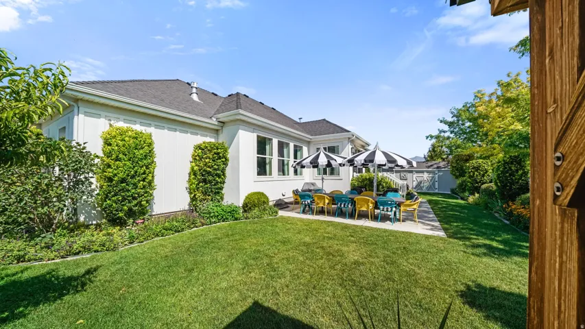 Expansive backyard featuring a manicured lawn, concrete patio, and established perimeter landscaping