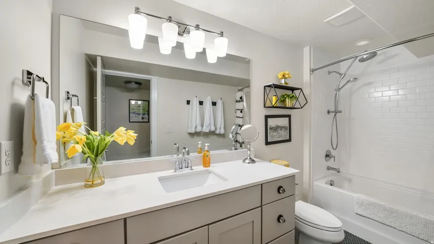 Bathroom featuring a light-toned countertop vanity with an integrated sink, polished chrome faucet, and a wide mirror
