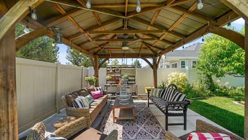 Outdoor gazebo featuring a corrugated metal roof, exposed wood beams, and string lighting