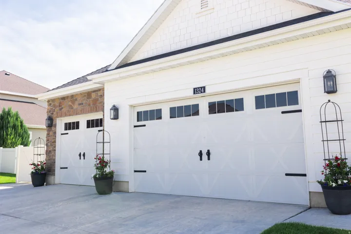 Two white garage doors with black hardware and upper window panels
