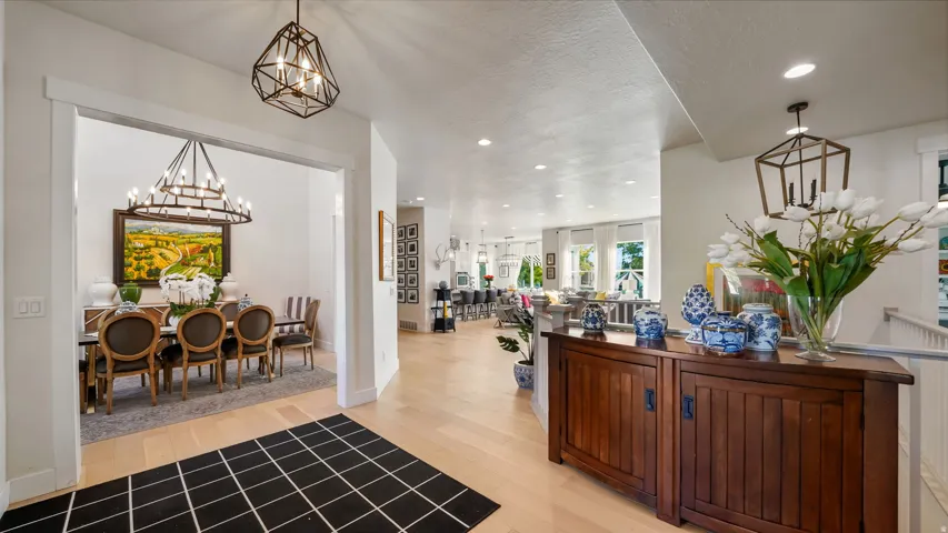 Open concept entry foyer featuring light wood-finish flooring, white walls, recessed lighting, and a modern geometric chandelier