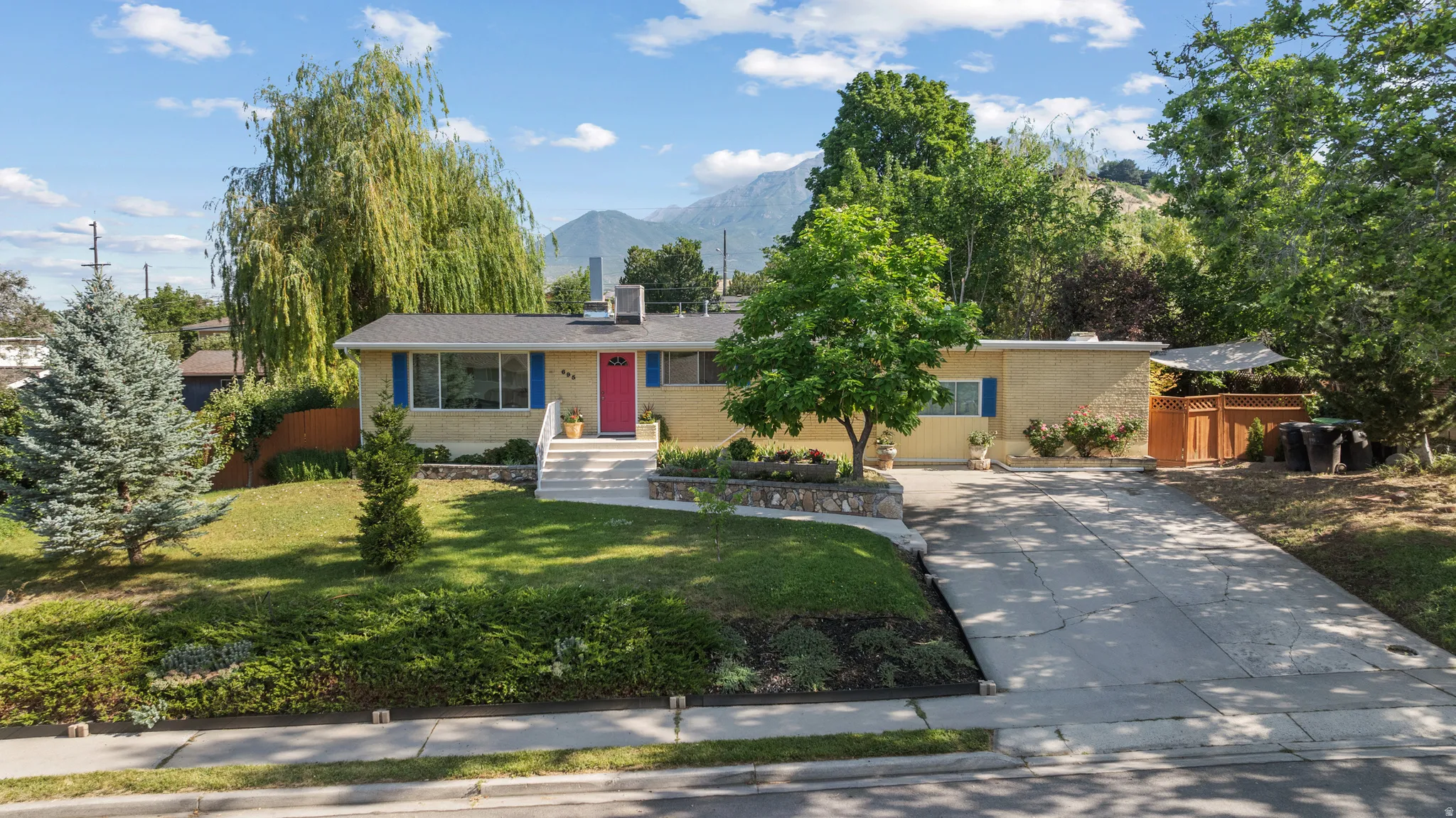 Ranch-style residence featuring a yellow exterior with blue window shutters and a vibrant red entry door
