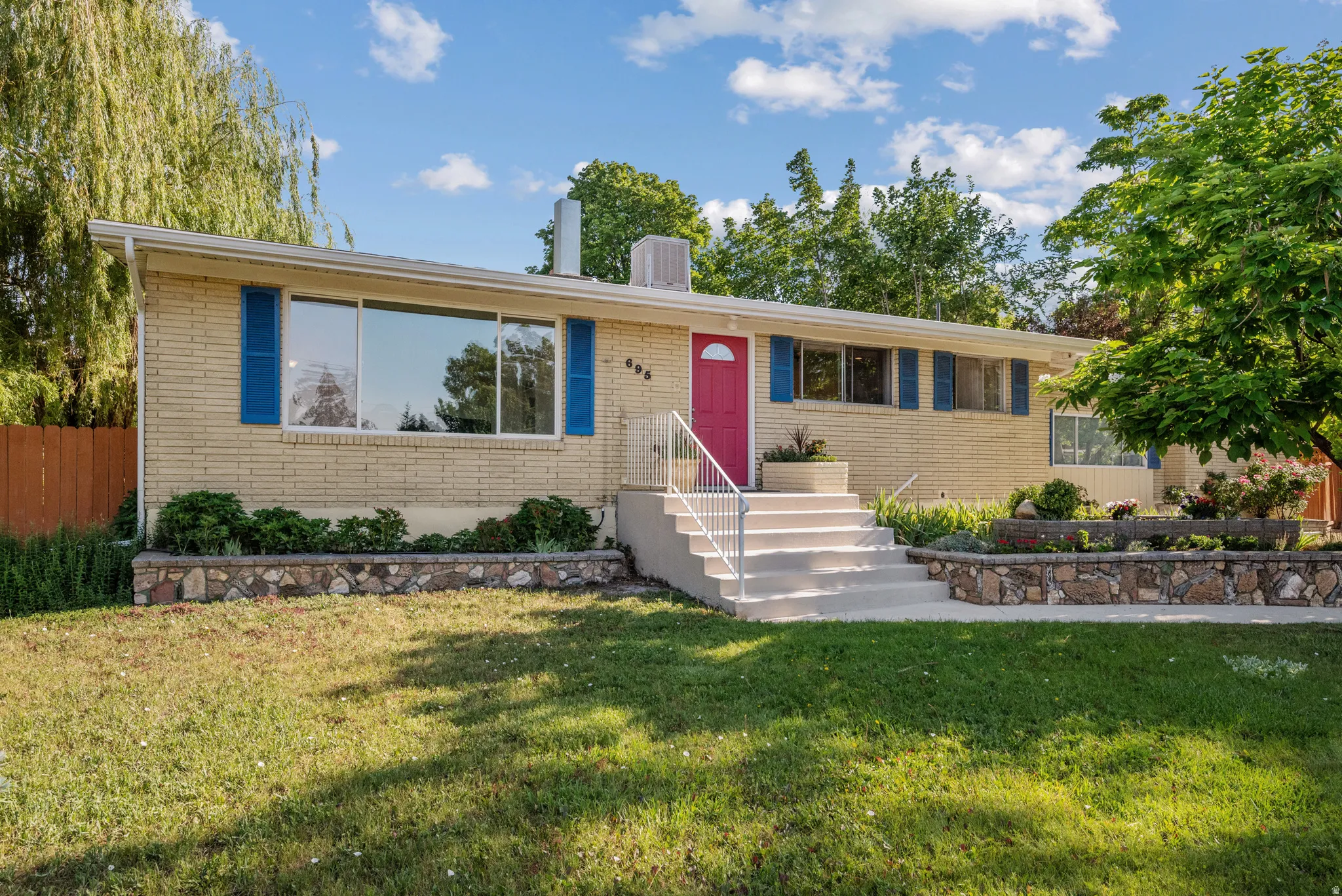 Ranch-style residence featuring light brick exterior and a vibrant red entry door