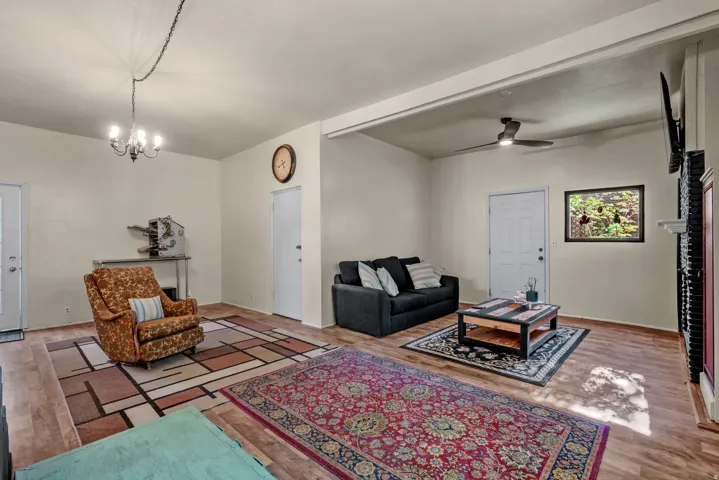 Spacious living area featuring wood-finish flooring, a ceiling fan, and a chandelier