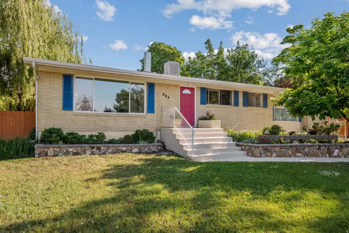 Ranch-style residence featuring light brick exterior and a vibrant red entry door