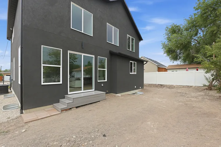 Modern two-story exterior with dark grey stucco siding and white trim windows