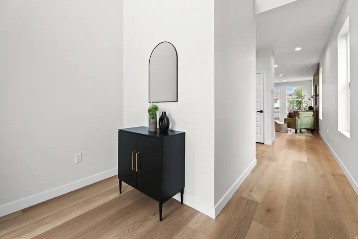 Bright hallway featuring light wood-finish flooring, white baseboards, and recessed lighting