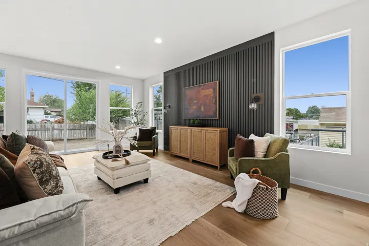 Living space featuring ample natural light, light wood-finish flooring, and a dark accent wall with vertical paneling