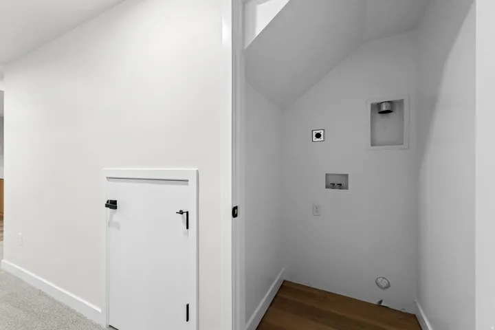 Dedicated laundry area featuring wood-finish flooring, a dryer vent, washing machine hookups, and a wall outlet