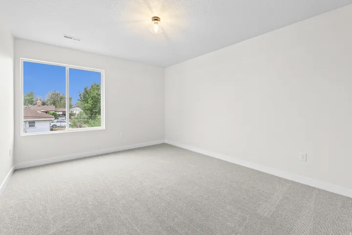 Bright room featuring a large double window, light-toned carpeting, white baseboards, and a single ceiling light fixture