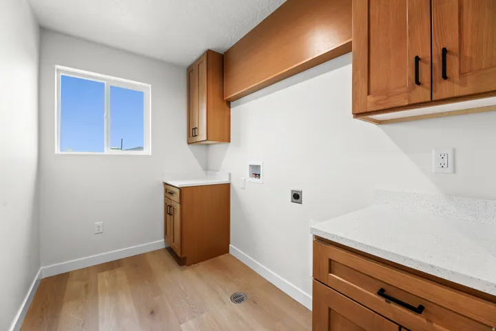 Utility room featuring light wood-finish flooring, white walls, and a window providing natural illumination