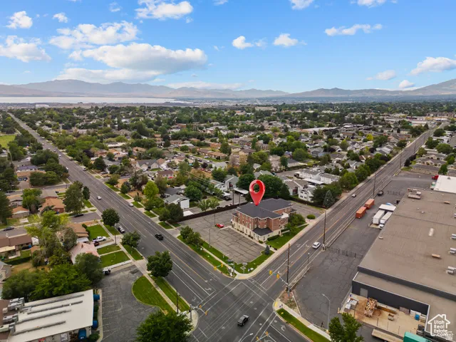 Corner lot property featuring brick exterior construction, a paved parking area, mature trees, and a prominent position within a developed neighborhood