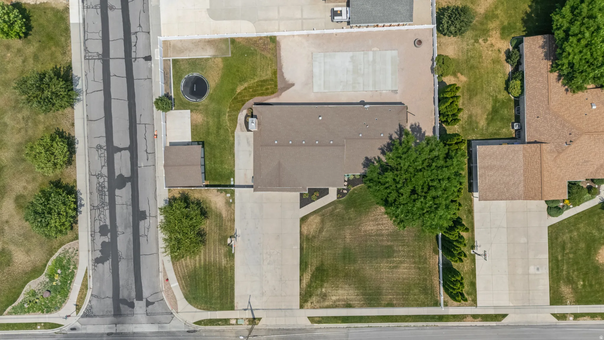 Expansive lot featuring a single-story residence with a brown shingle roof, a detached shed, a long concrete driveway, and a concrete patio area