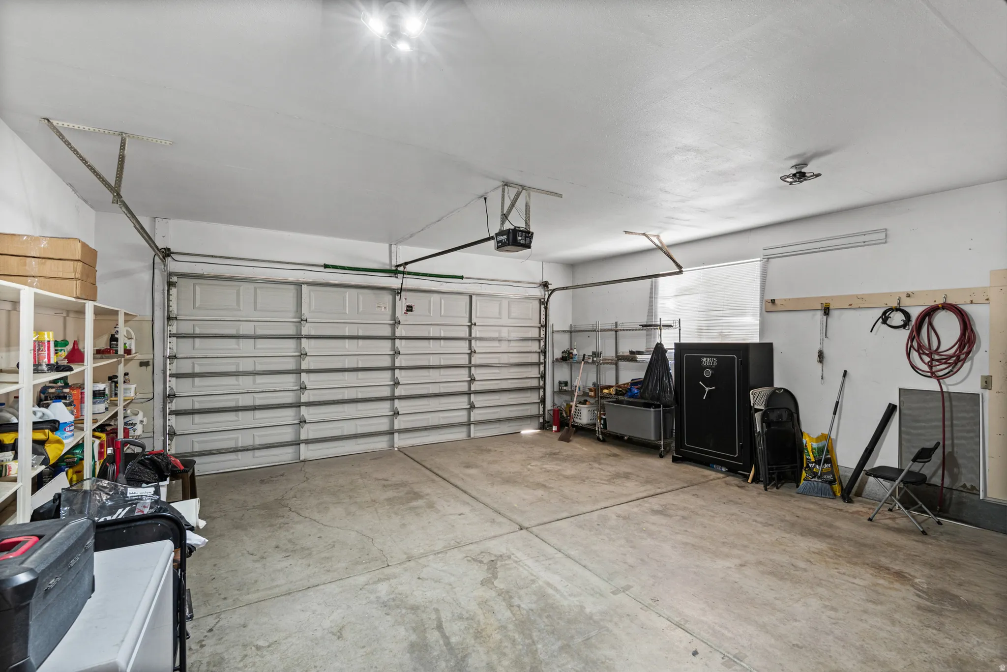 Two-car garage featuring a concrete floor, built-in shelving, and a rear window for natural light
