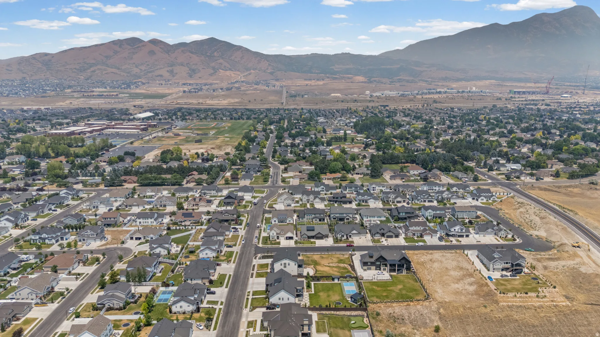 Expansive residential area featuring a grid of paved streets and numerous single-family homes, with mountain ranges forming a dramatic backdrop