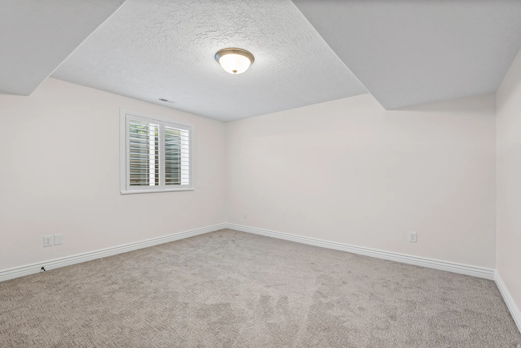 Room featuring neutral-toned walls, textured carpet flooring, and white baseboards