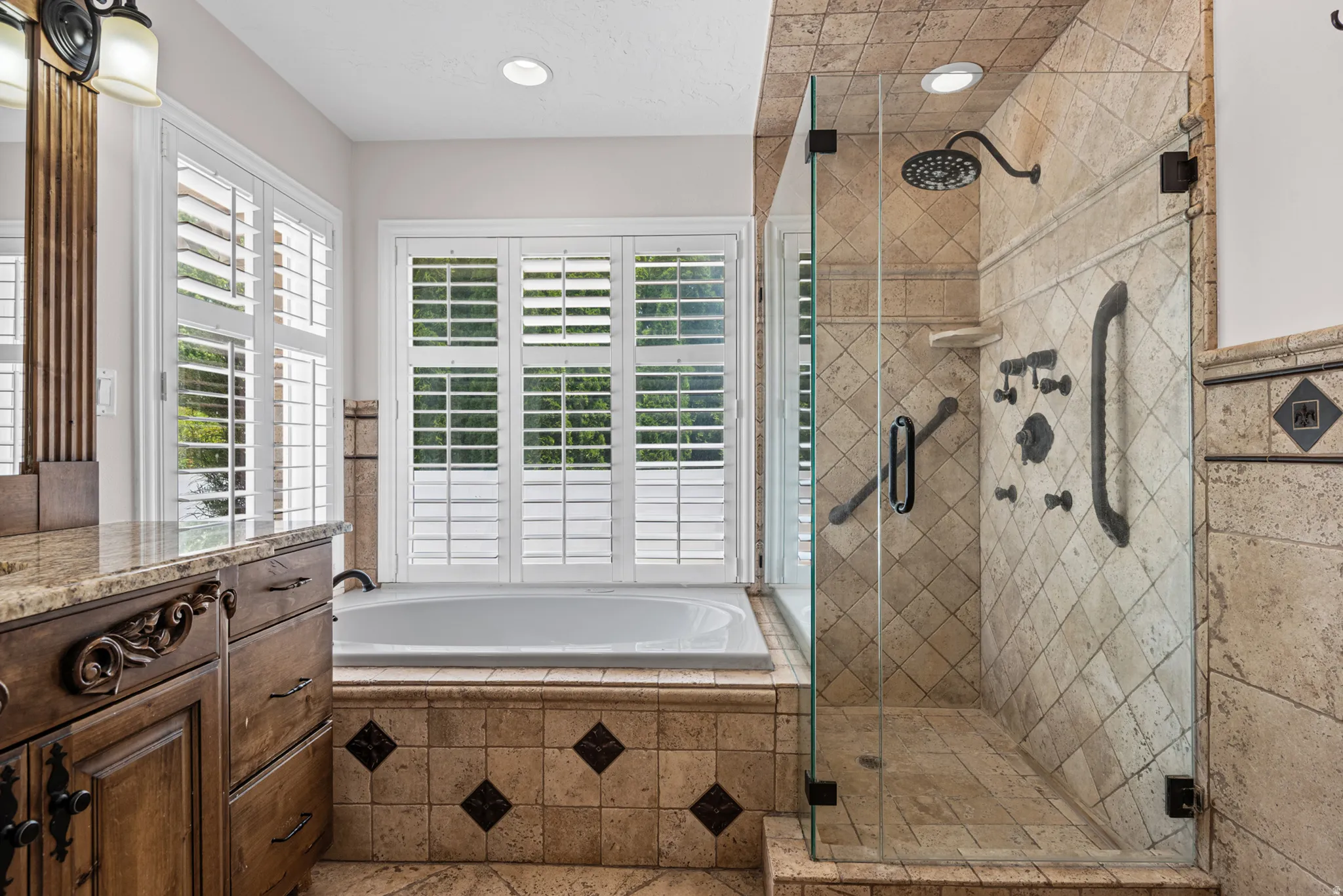 Tiled bathroom featuring a glass-enclosed shower, built-in bathtub, and a wood-finish vanity with a stone countertop