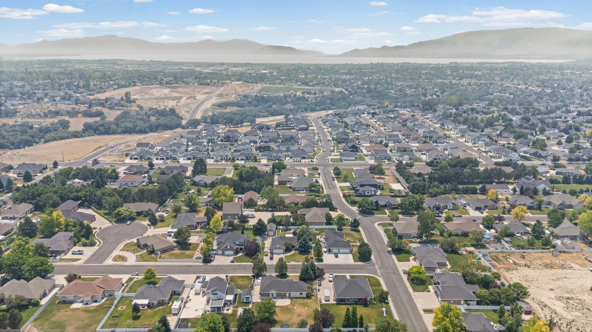 Expansive aerial perspective showcasing a developed residential neighborhood with established homes and tree-lined streets