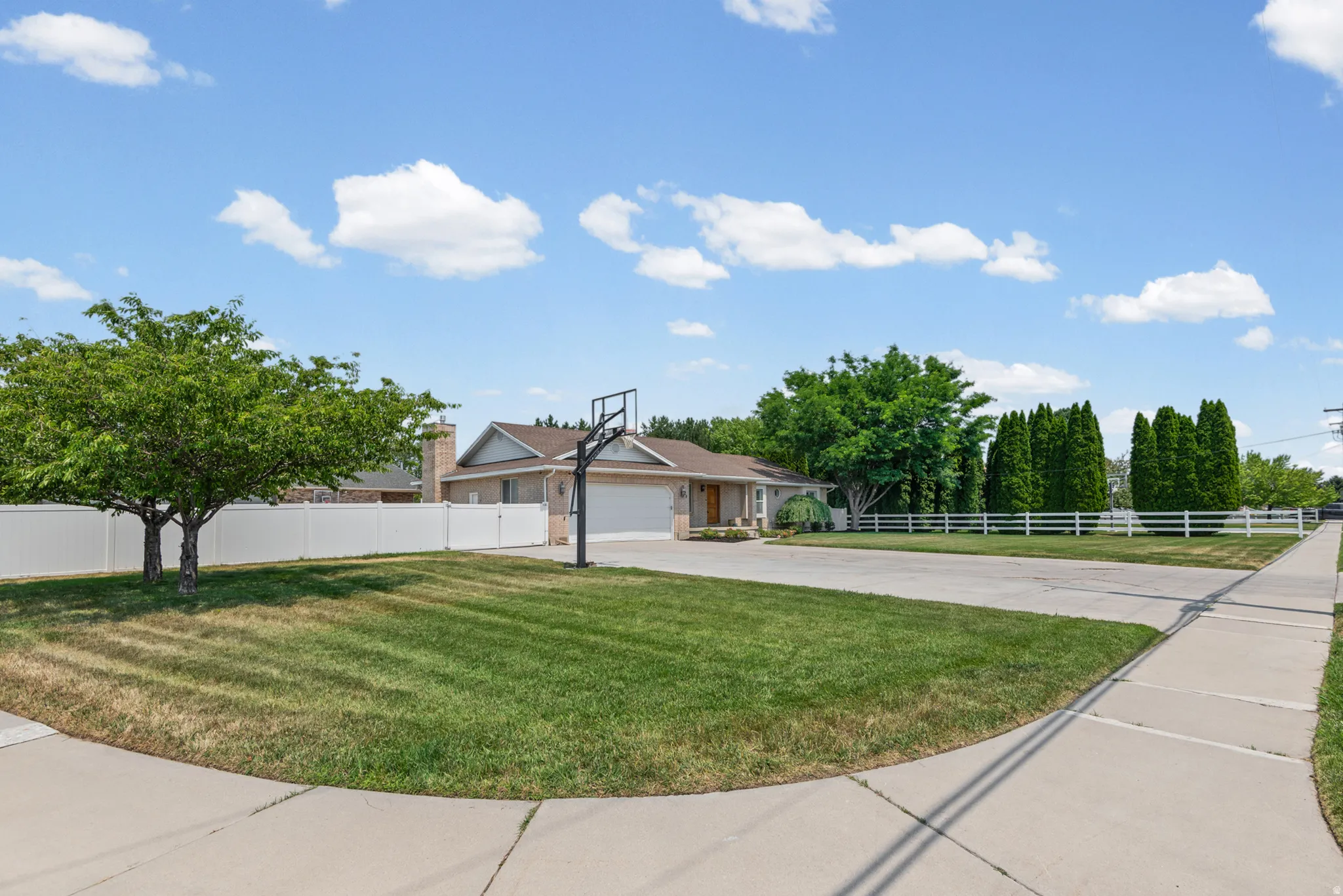 Ranch-style exterior with a two-car garage, featuring a concrete driveway and sidewalk