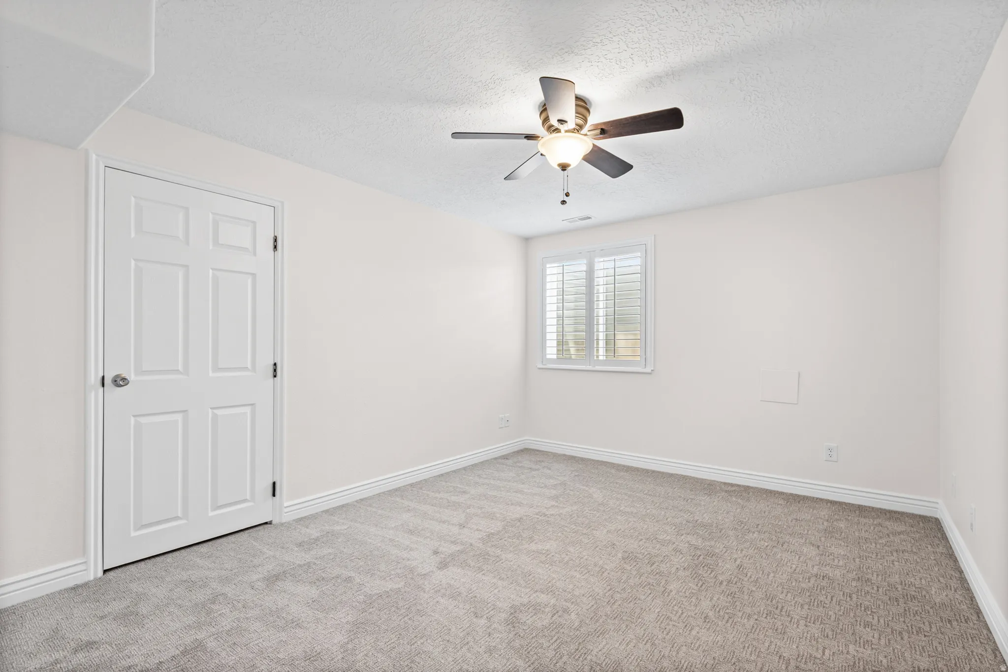 Spacious interior room with light neutral walls and gray carpet flooring