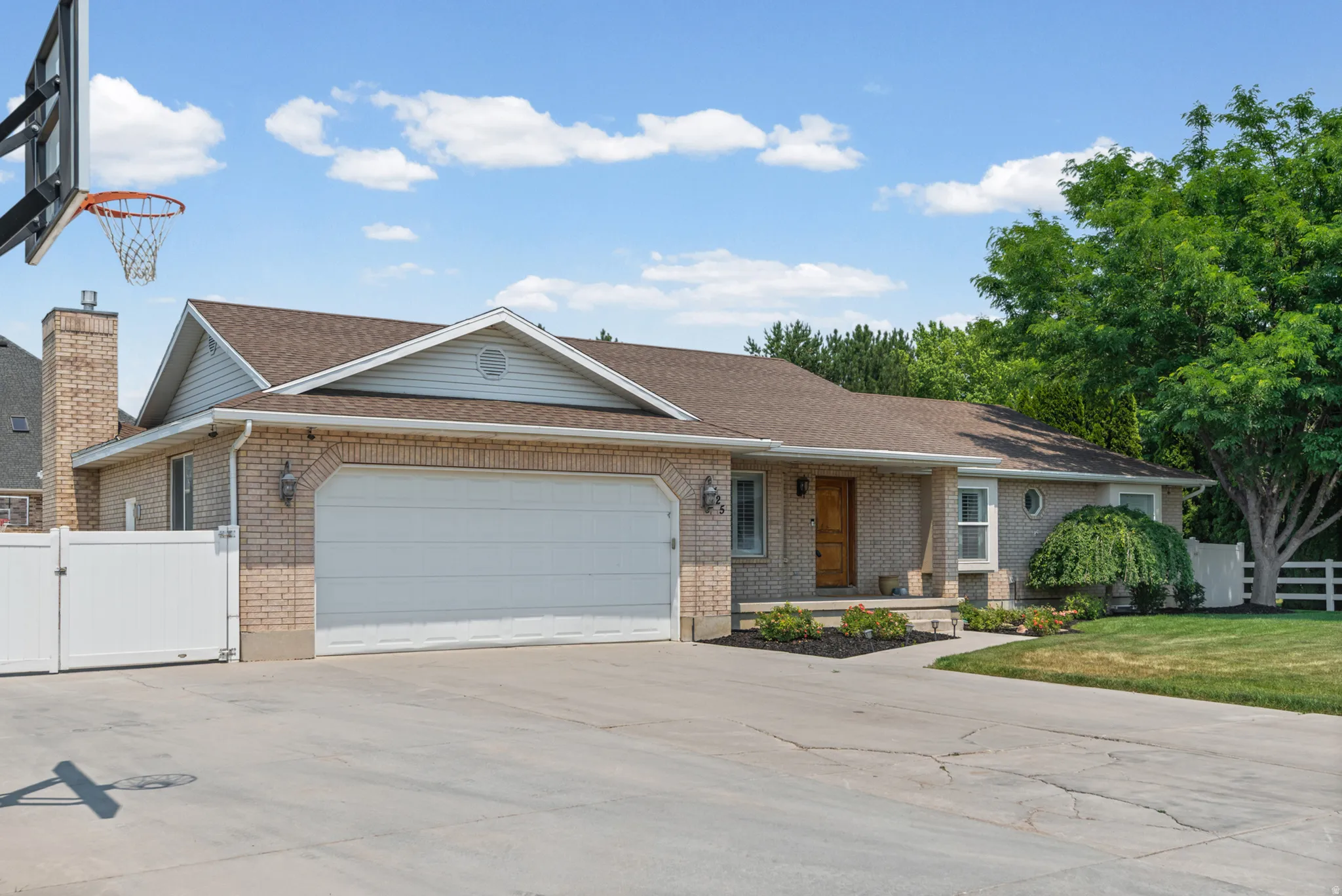 Brick exterior ranch-style home featuring a two-car garage, an arched garage door, a prominent chimney, and a front porch