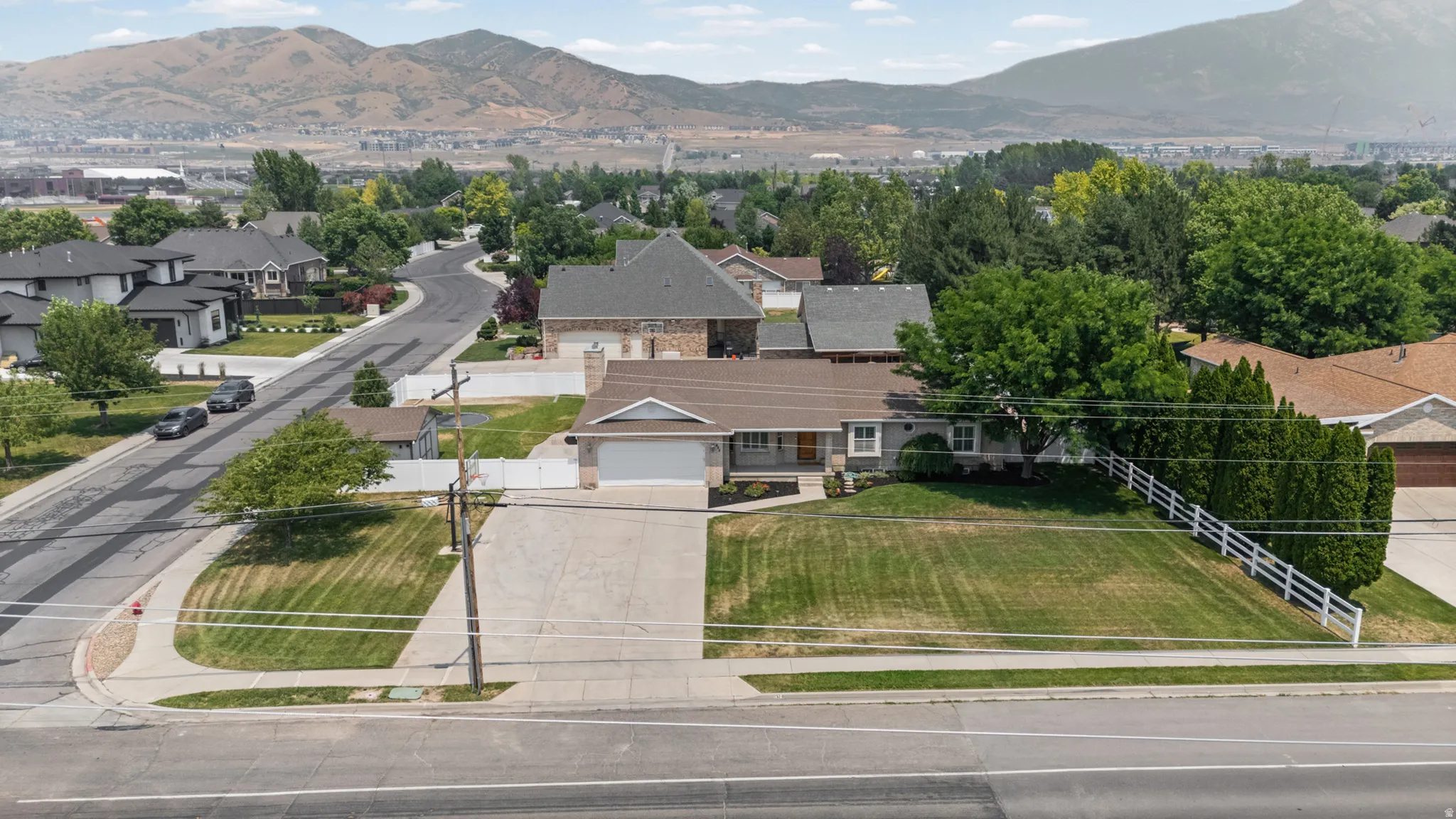 Single-story residence featuring an attached garage, a paved driveway, and a front lawn with mature trees and shrubs