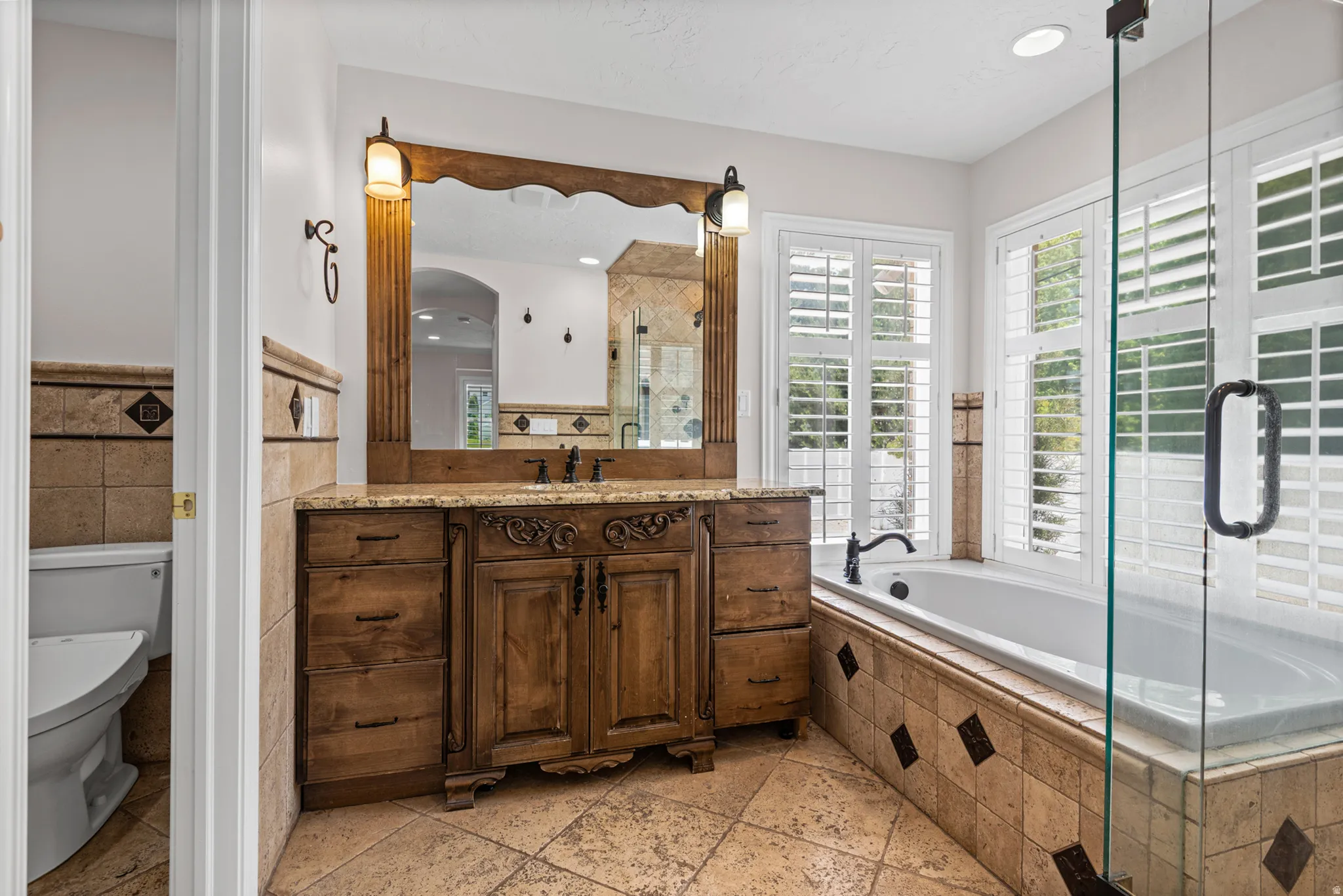 Bathroom featuring an ornate wooden vanity with dual sinks, a large framed mirror, and a built-in bathtub with tiled surround