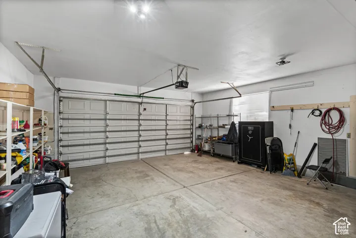 Two-car garage featuring a concrete floor, built-in shelving, and a rear window for natural light
