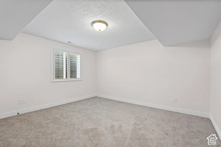 Room featuring neutral-toned walls, textured carpet flooring, and white baseboards