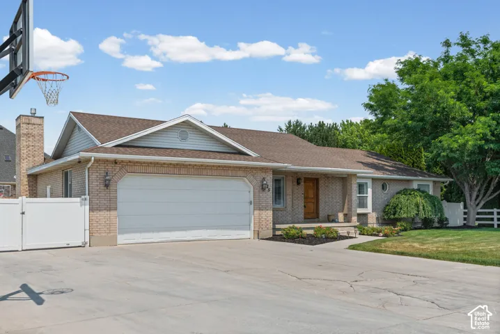 Brick exterior ranch-style home featuring a two-car garage, an arched garage door, a prominent chimney, and a front porch