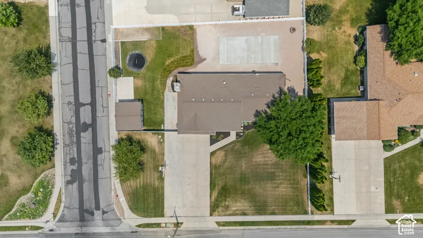 Expansive lot featuring a single-story residence with a brown shingle roof, a detached shed, a long concrete driveway, and a concrete patio area