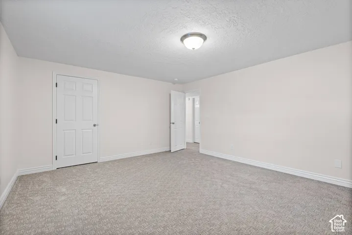 Spacious room featuring neutral carpeting, light-colored walls, white trim, and a semi-flush mount ceiling light fixture