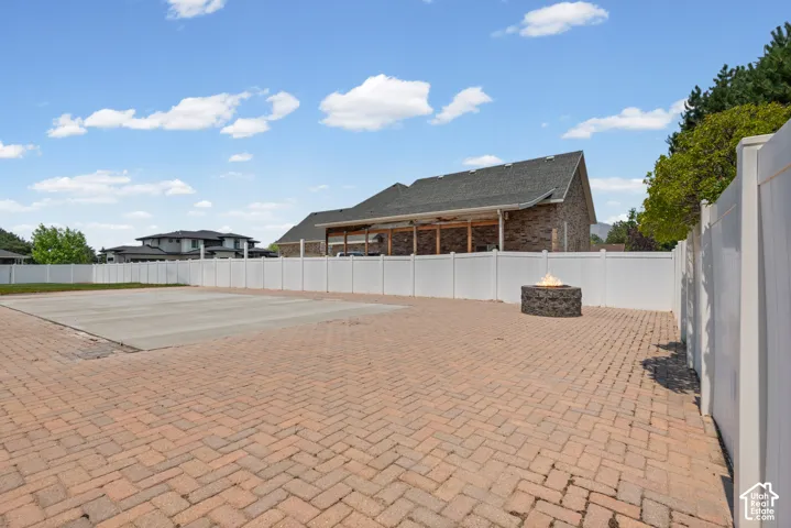 Expansive herringbone-patterned brick paver patio featuring a built-in stone fire pit