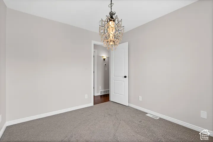 Neutral-toned room featuring a crystal chandelier, light gray walls, white trim, and gray carpeting