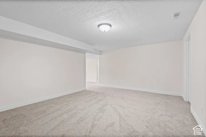 Spacious room with new carpeting, light neutral wall paint, and white trim