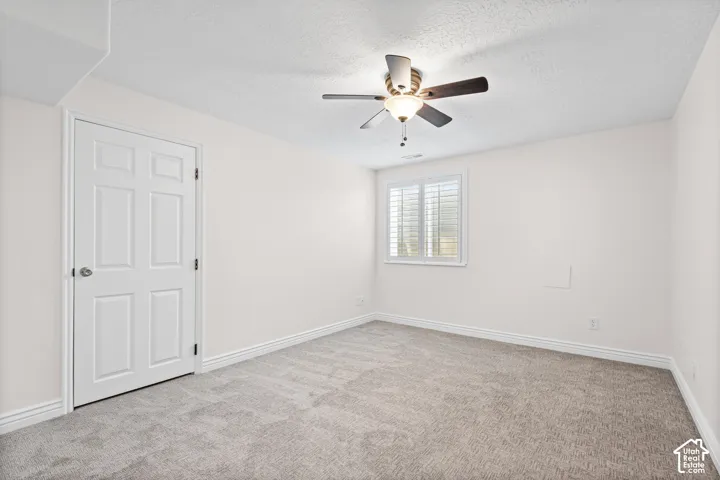 Spacious interior room with light neutral walls and gray carpet flooring