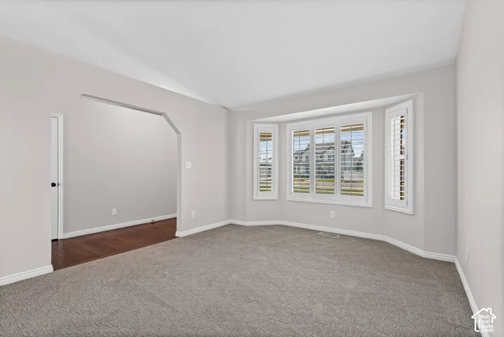 Spacious room with a large bay window featuring white plantation shutters
