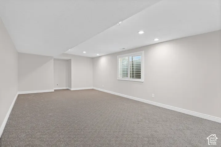 Spacious room featuring neutral carpeting, light-toned walls, and recessed lighting
