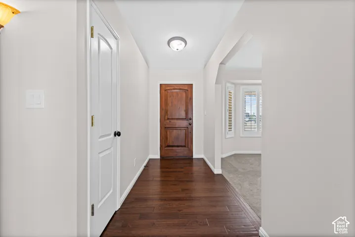 Rich wood-finish flooring extending from the entryway, a paneled front door, and a recessed ceiling light