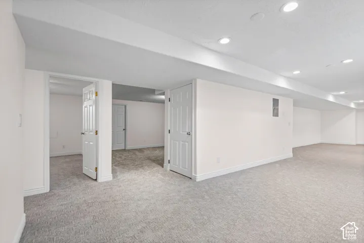 Spacious finished basement featuring recessed lighting, light-toned carpeting, white trim, and multiple doorways
