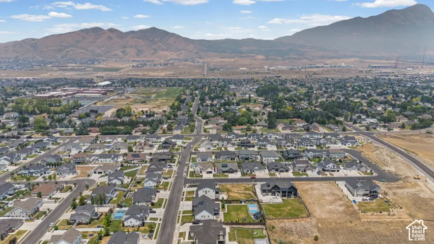 Expansive residential area featuring a grid of paved streets and numerous single-family homes, with mountain ranges forming a dramatic backdrop
