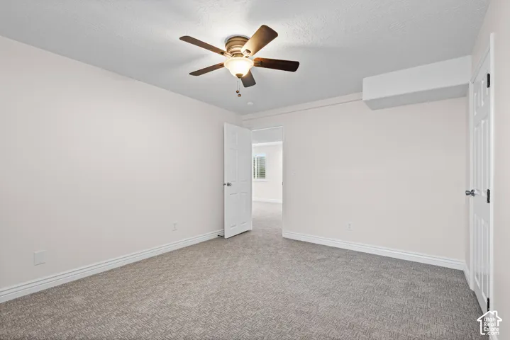 Carpeted room with a ceiling fan light fixture, white interior door, and a wall-mounted air conditioning unit