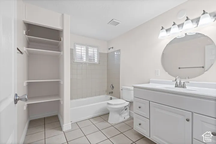 Full bathroom featuring a white vanity with integrated sink, a rectangular mirror, a bathtub with tile surround, and built-in shelving