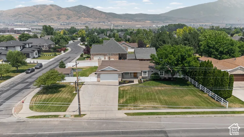 Single-story residence featuring an attached garage, a paved driveway, and a front lawn with mature trees and shrubs