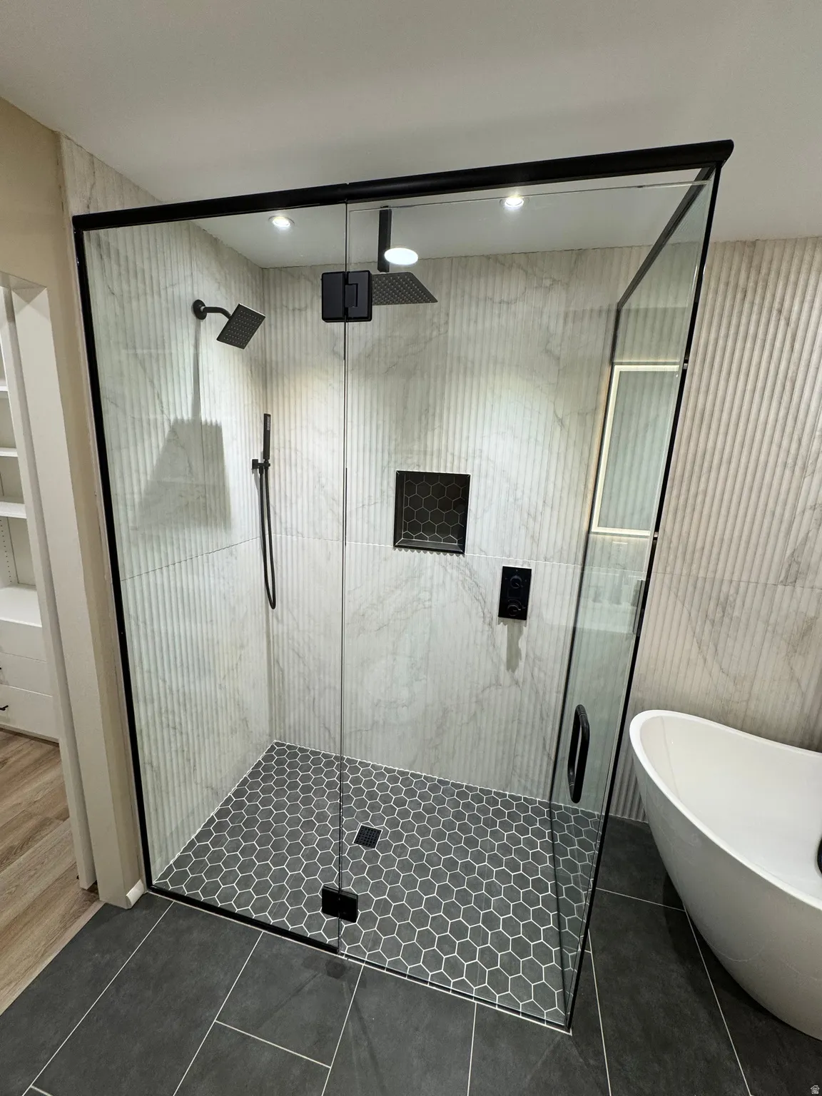 Frameless glass-enclosed shower with black metal trim